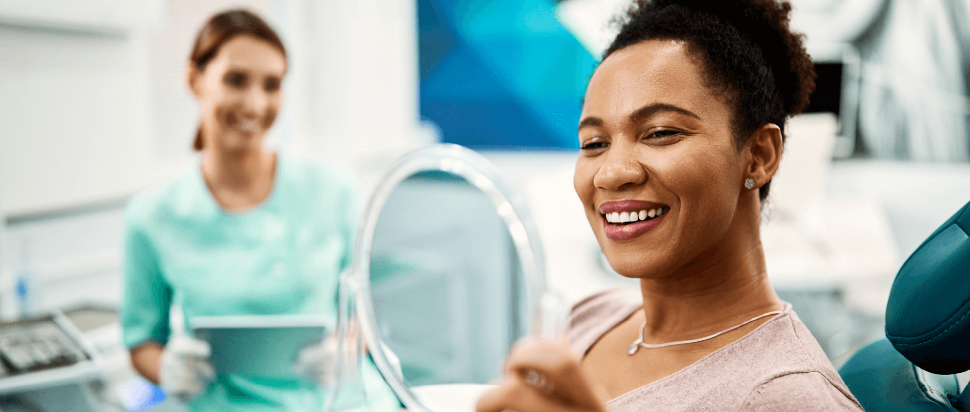 A female patient checks out her beautiful smile in a handheld mirror.