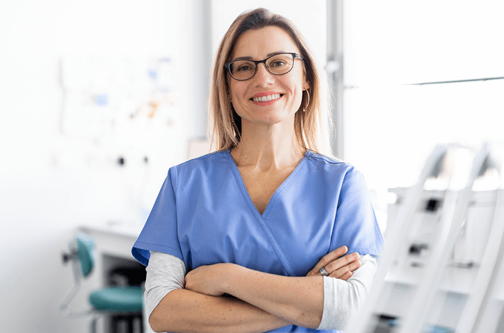 A female hygienist crosses her arms and smiles.