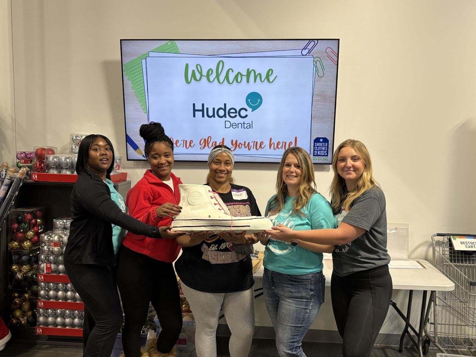 Hudec Dental employees holding large shoe at community service event