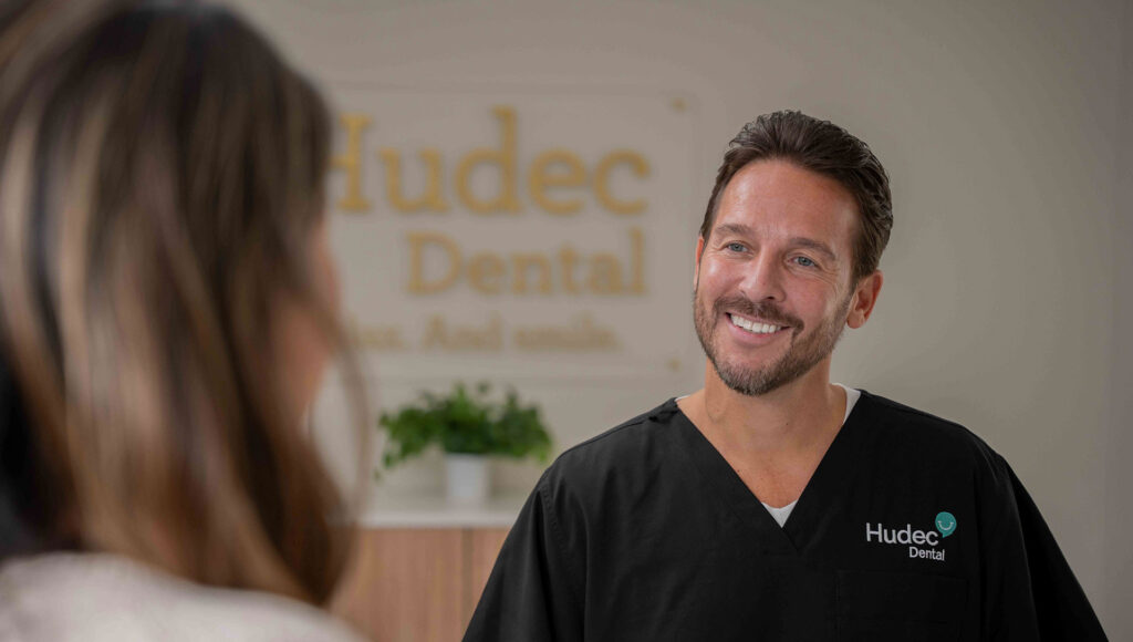 Dentist smiling while speaking with a patient in a dental office