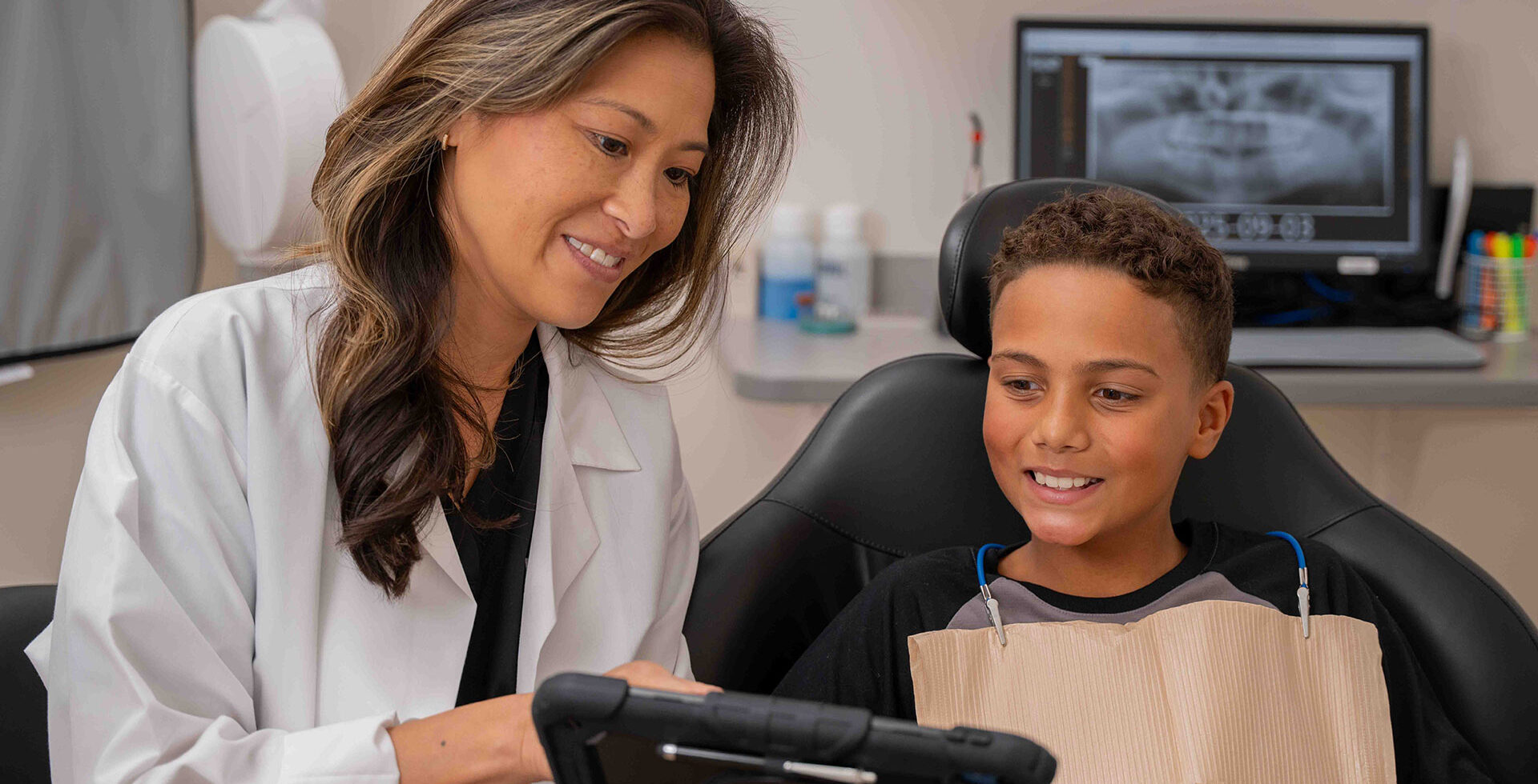 Dentist showing a young patient images on a tablet during a dental appointment