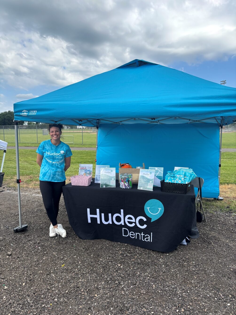 Hudec Dental team member standing next to their tent and table at the Macedonia 5K Run/Walk