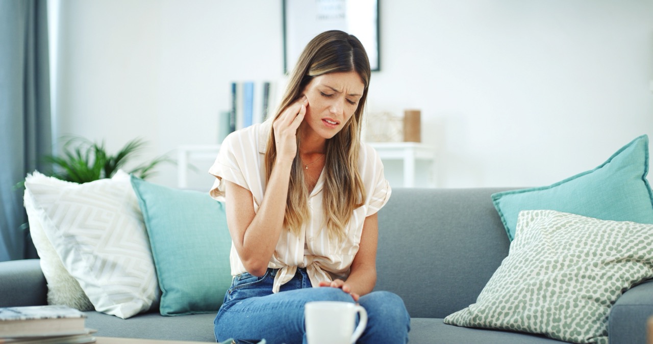 Frustrated woman, pain and sofa with tooth ache for dental emergencies, jaw infection or gum disease at home. Female person, decay or sore teeth in discomfort for mouth cavity, illness or swollen abscess