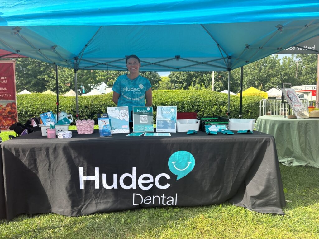 A Hudec Dental employee standing behind the Hudec table at the 2026 Cleveland Garlic Festival